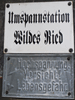 Stationsbezeichnung und Warnschild am Trafoturm Wildes Ried